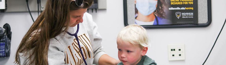 Student in pediatrics class at Millersville University examines a young child.